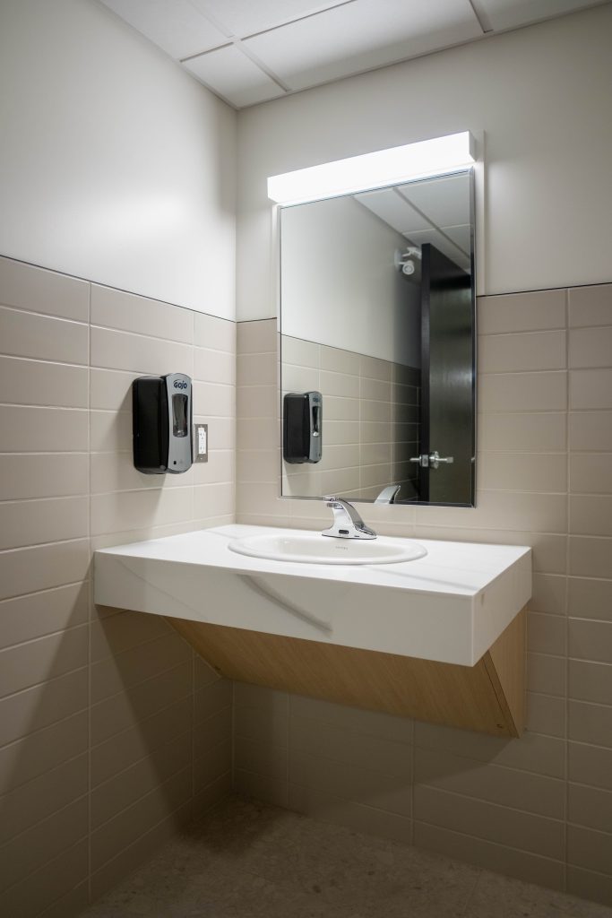 A modern washroom with accessible sink features a counter with Maple White Quartz provided by CNG Stone.